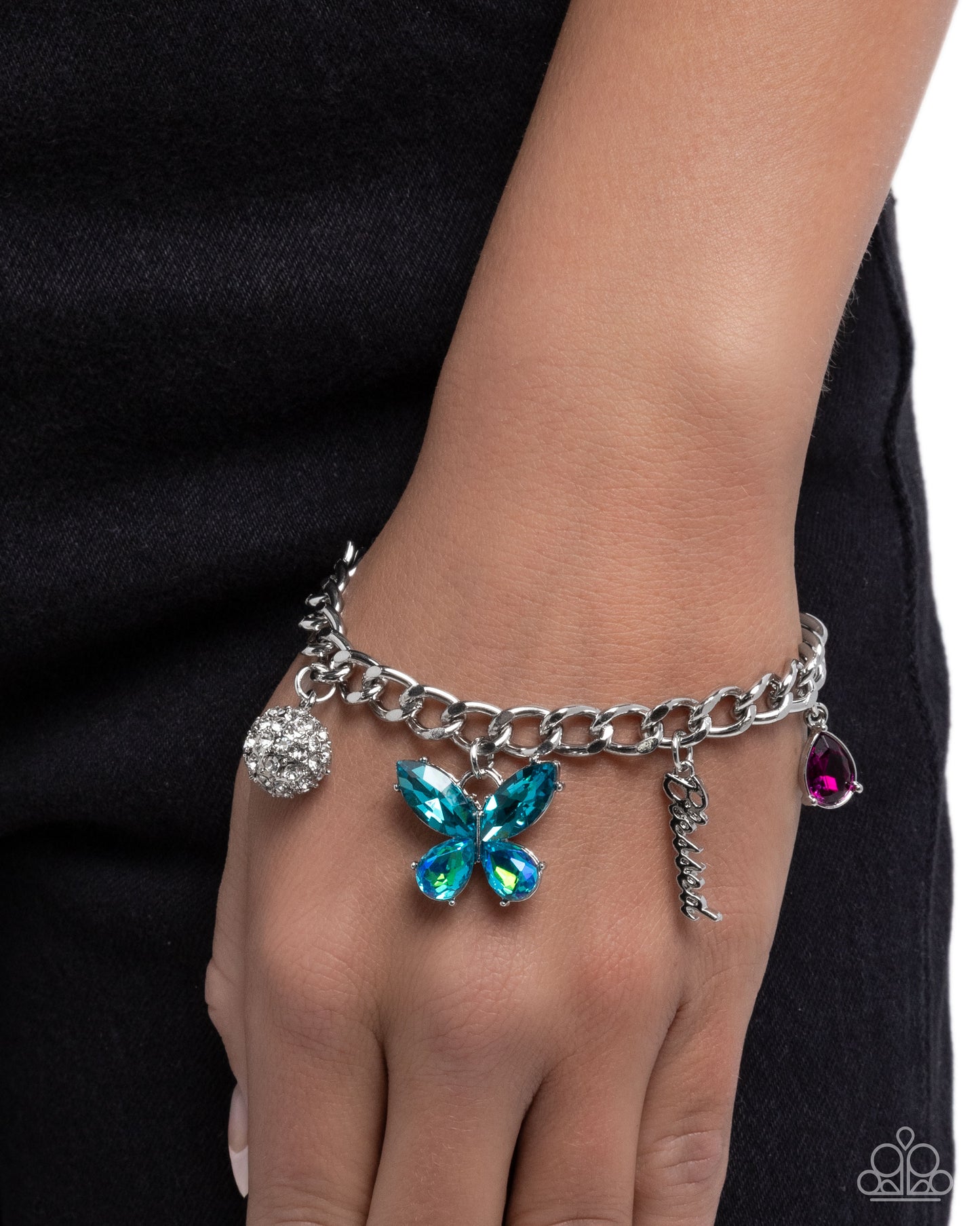 Bracelet with colorful charms on a wrist against a black background