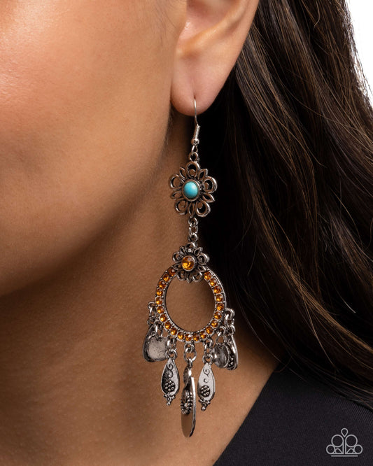 Close-up of an ornate earring with a turquoise gemstone worn by a person.