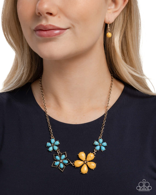 Necklace with blue and yellow floral pendants worn by a model on a white background