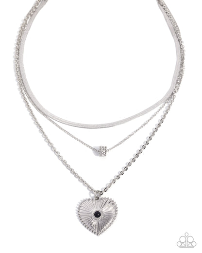Stack of silver necklaces with heart pendant on a white background