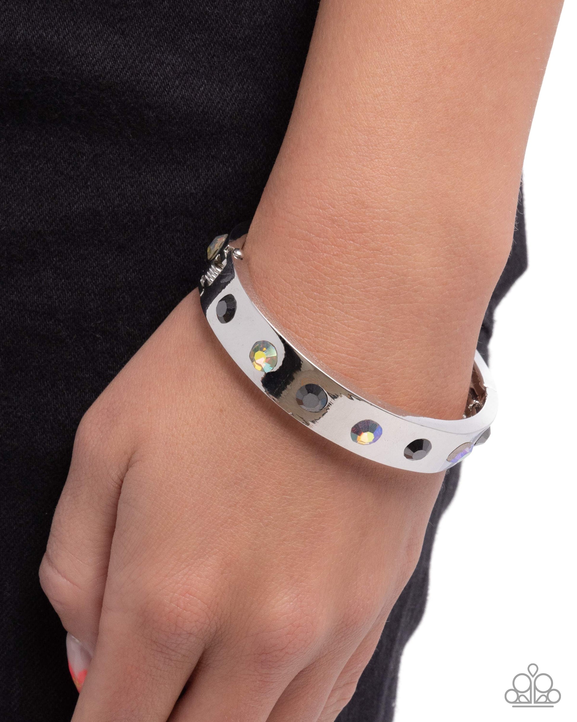 Silver bracelet with gemstones on a wrist against a black background