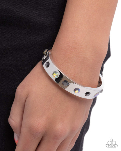 Silver bracelet with gemstones on a wrist against a black background