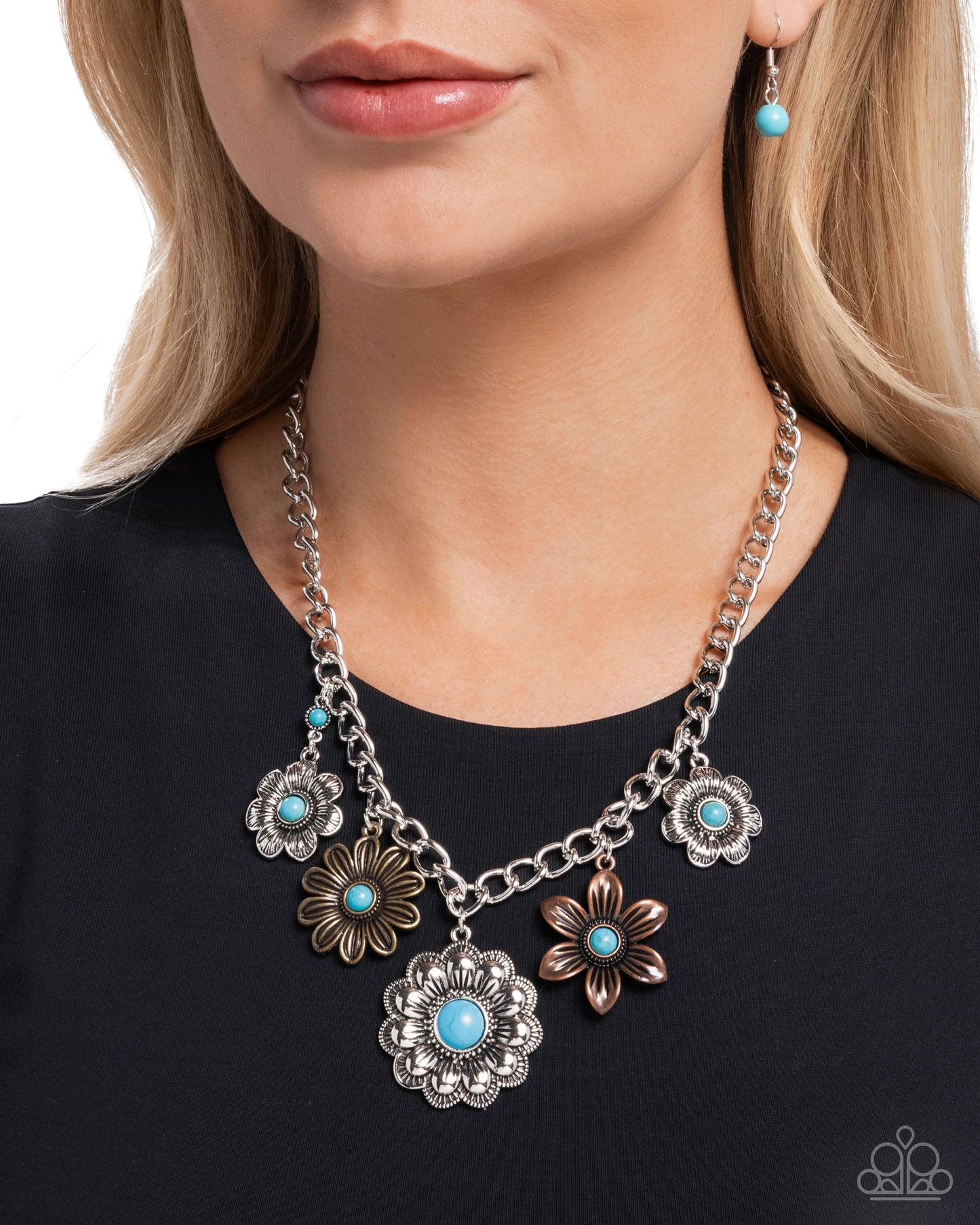 Necklace with floral pendants and turquoise stones worn by a person on a black background