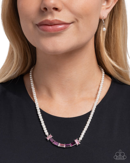 Pearl necklace with pink gemstones worn by a model on a white background
