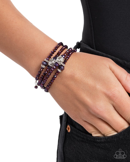 Purple beaded bracelet on a wrist with a white background