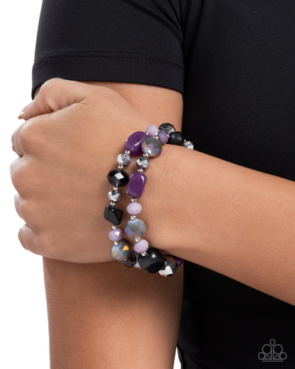 Multicolored beaded bracelet on a wrist with a black sleeve
