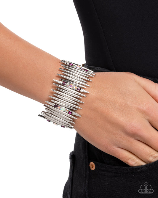 Silver bracelet with gemstones on a wrist against a black background