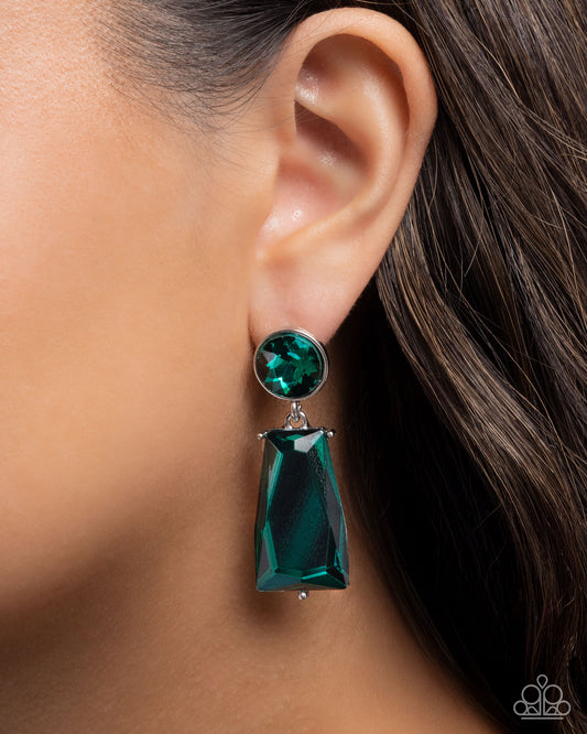Close-up of an ear wearing a green earring with a blurred background