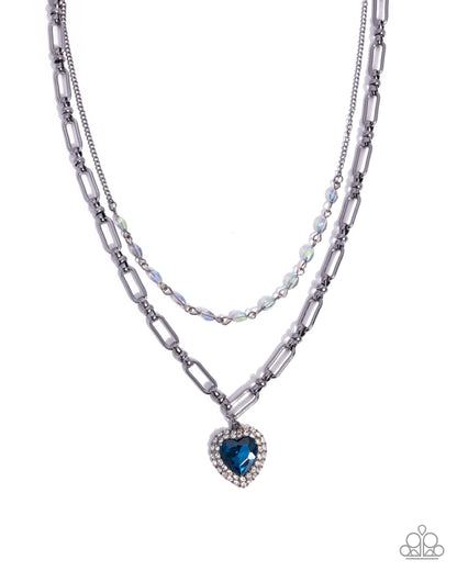 Two layered necklaces with a heart-shaped blue gemstone pendant on a white background
