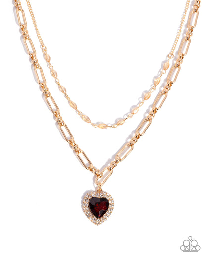 Layered gold necklaces with a heart-shaped garnet pendant on a white background