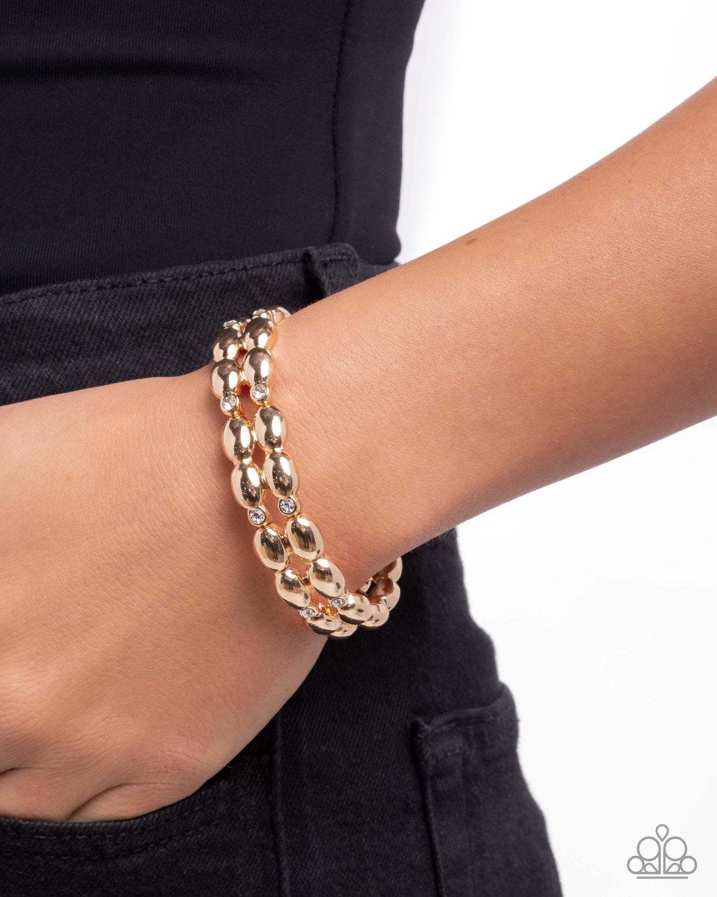 Gold bracelet on a wrist with a plain background