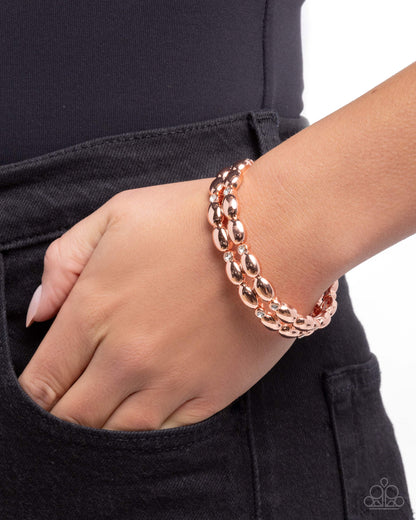 Rose gold bracelet on a wrist with a black background