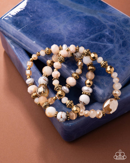 Set of beaded bracelets with gold accents on a blue textured surface