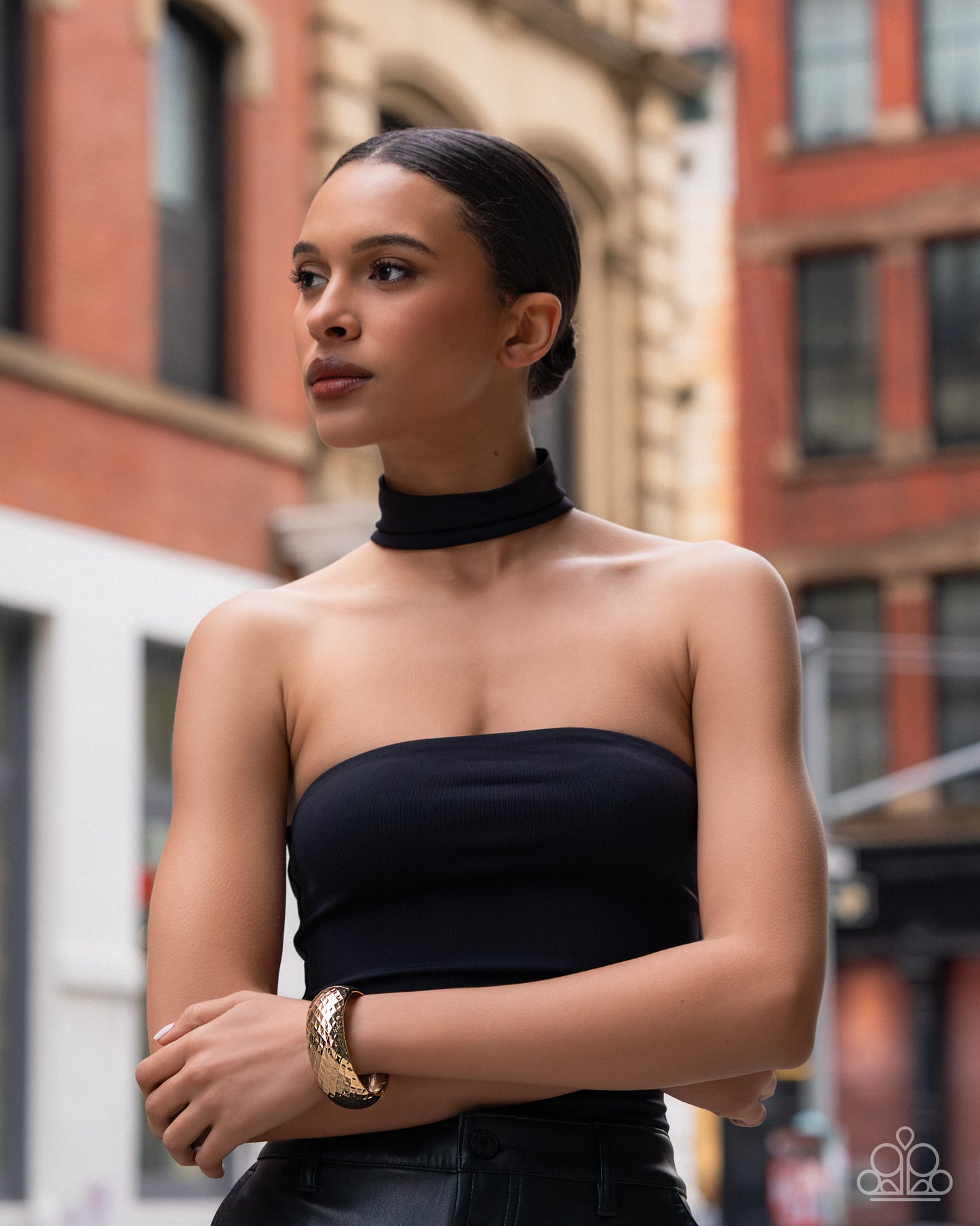 Woman wearing a black strapless top and high collar in an urban setting