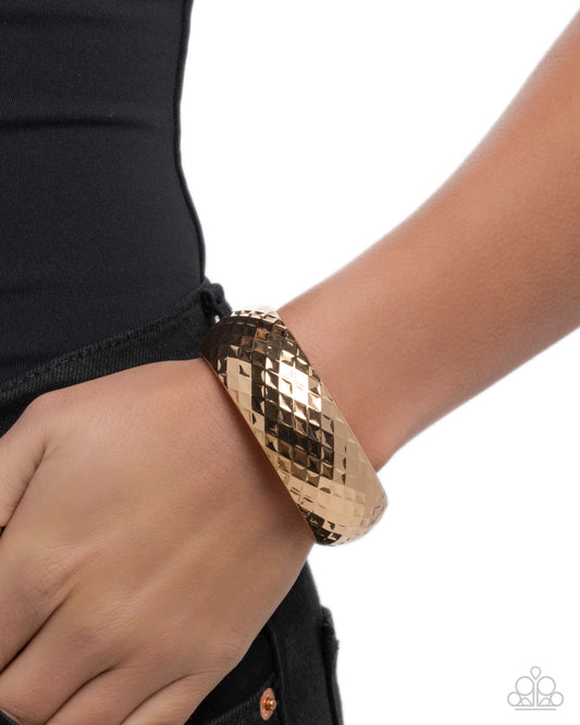 Gold bracelet on a wrist with a plain background