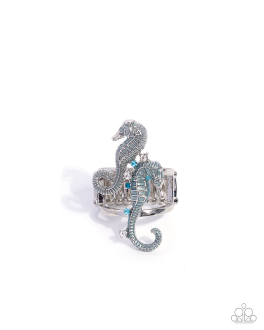 Silver seahorse-shaped ring with blue accents on a white background