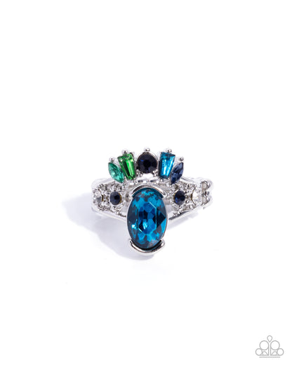 Elegant ring with blue gemstone and green and black accents on a white background