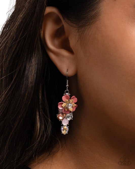 Close-up of an ear wearing a colorful floral earring with a brown background