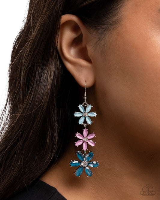 Close-up of an ear wearing a floral earring with blue and pink flowers.