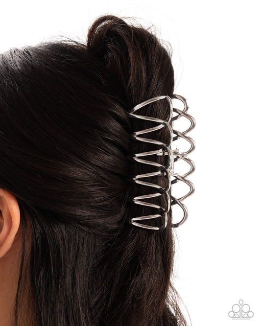 Silver hair bun holder in a person's dark hair on a white background