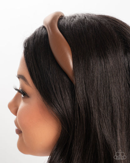 Woman wearing a brown headband with a plain background