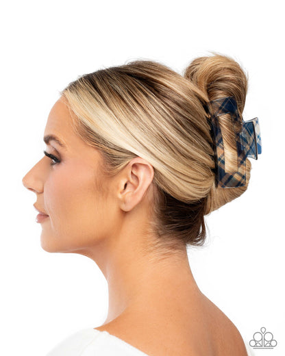 Woman with blonde hair styled in a bun with a blue plaid scrunchie on a white background