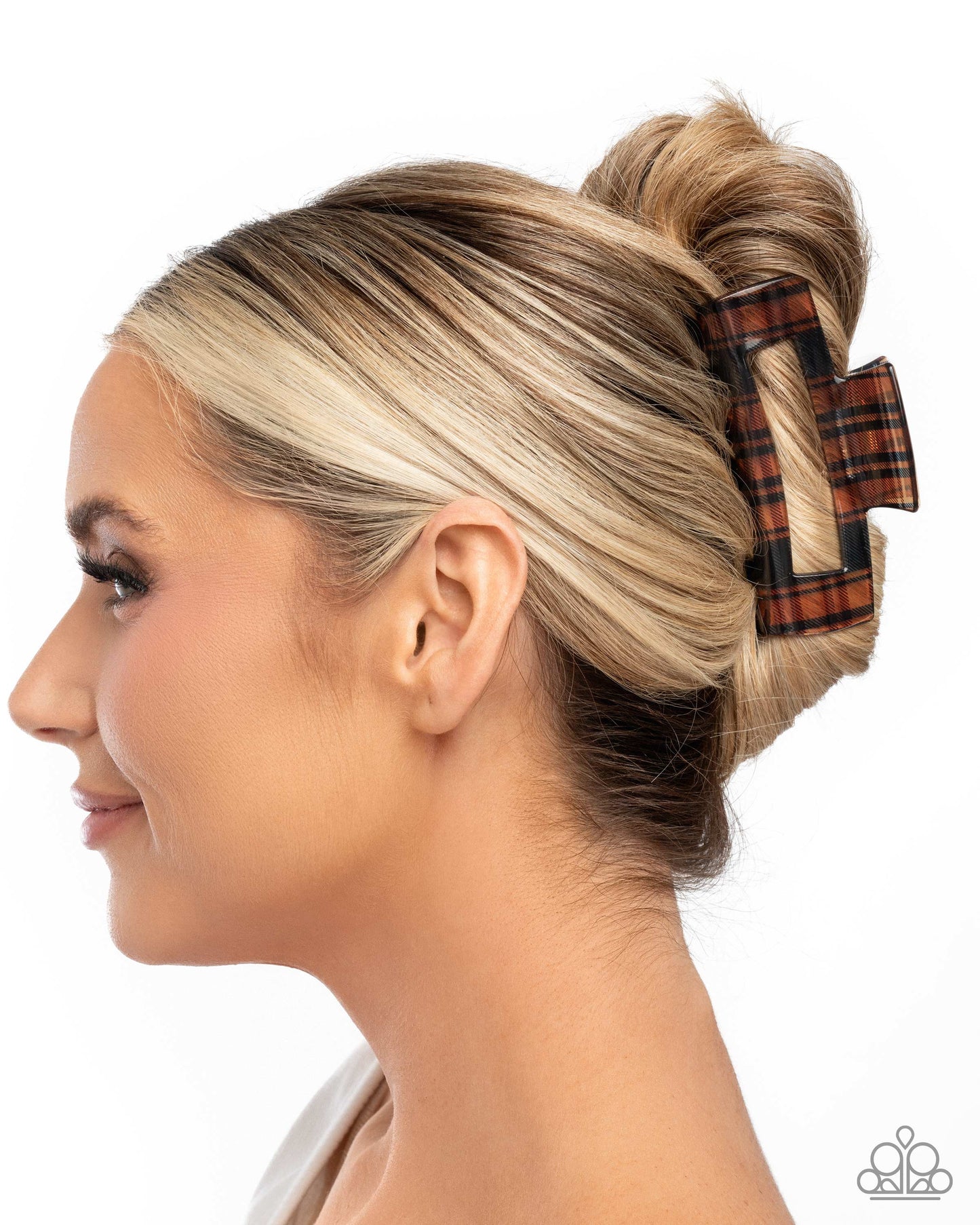 Woman with blonde hair styled in a bun with a plaid hair clip on a white background
