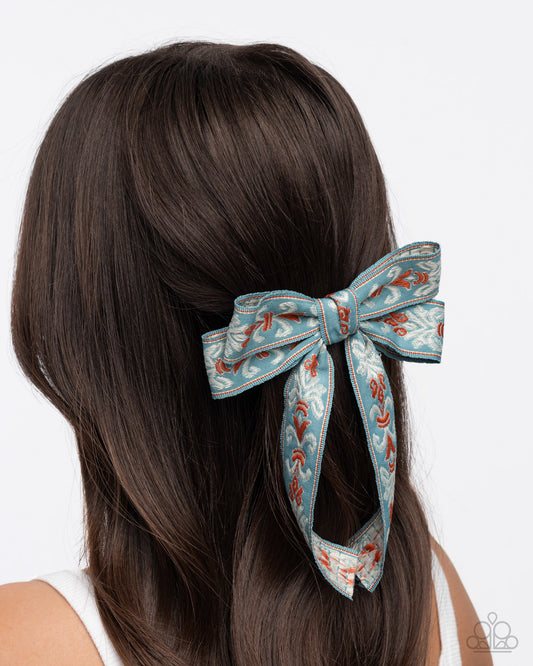 Hair bow accessory on a person with long brown hair against a white background