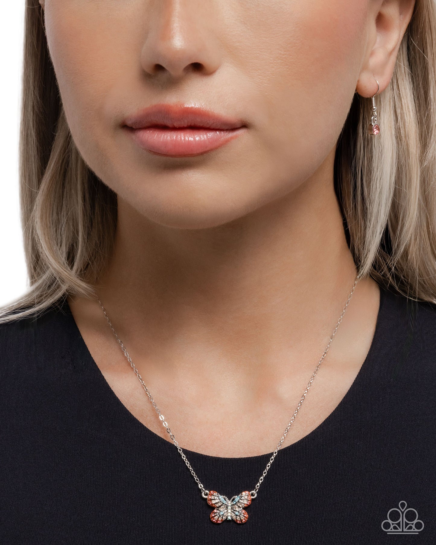 Close-up of a woman wearing a silver butterfly pendant necklace on a plain background