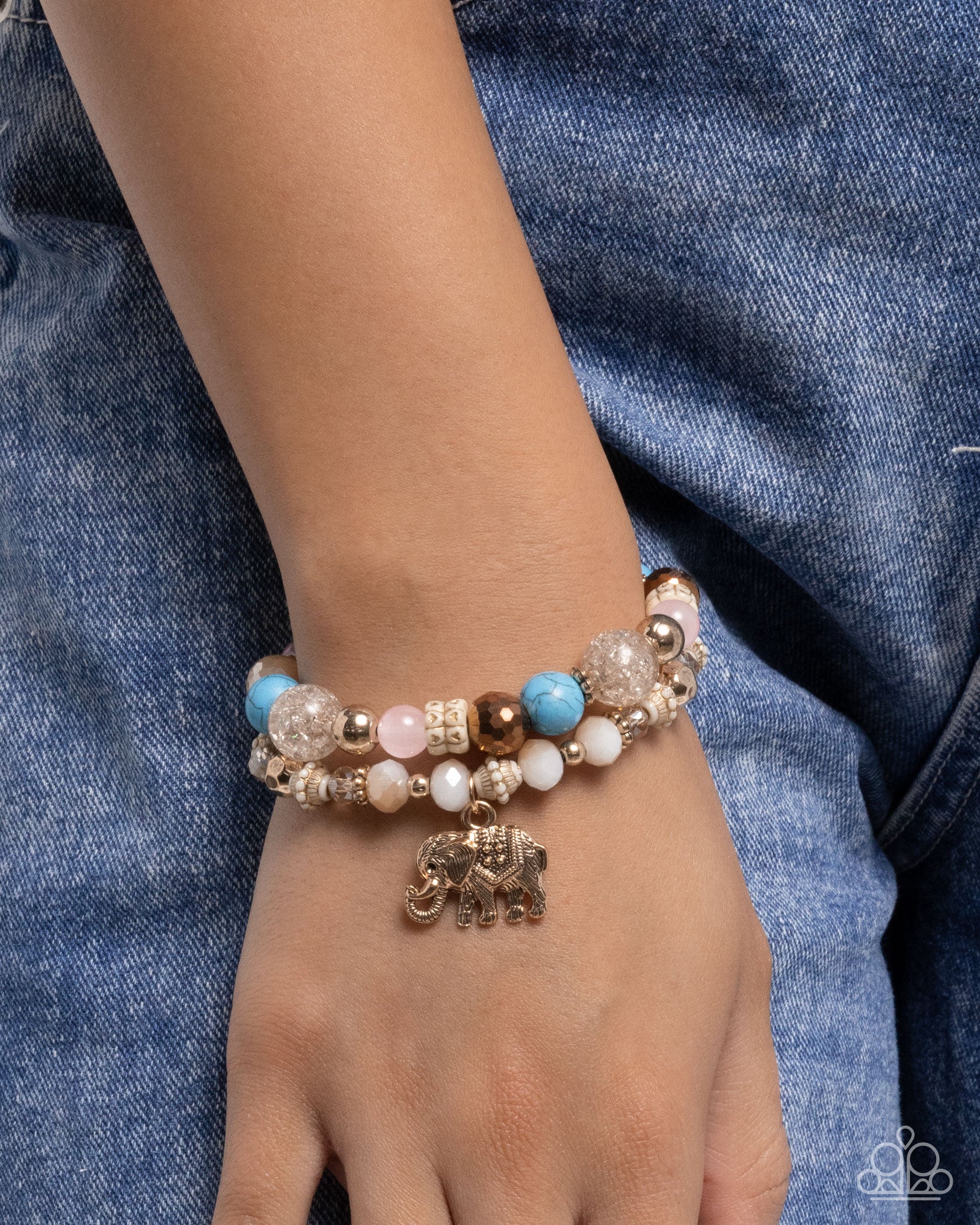 Bracelet with colorful beads and elephant charm on a wrist against a denim background