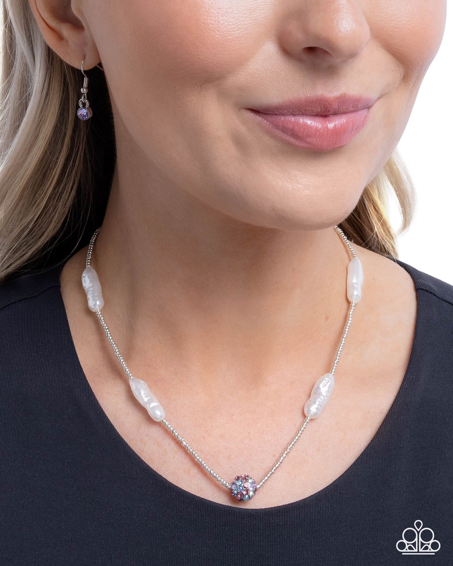 Woman wearing a pearl necklace with a black top against a white background