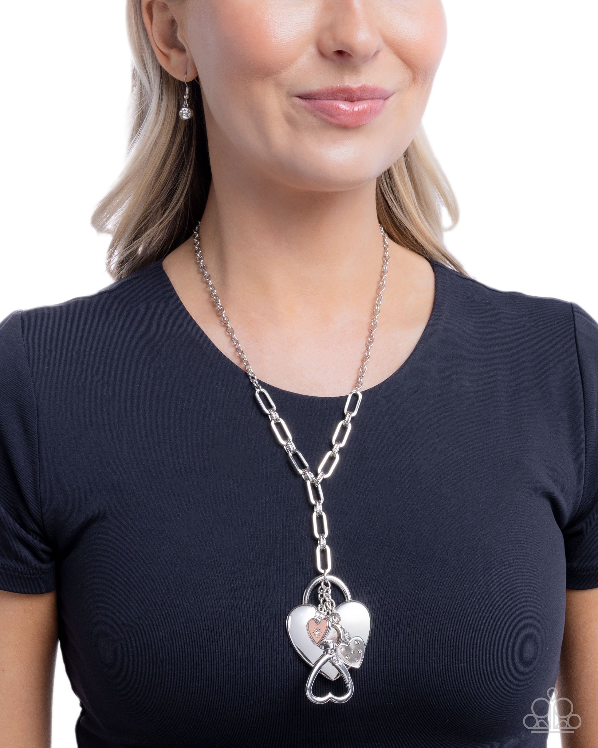 Woman wearing a silver chain necklace with a heart-shaped pendant on a white background