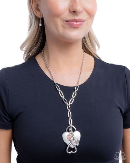 Woman wearing a silver chain necklace with a heart-shaped pendant on a white background
