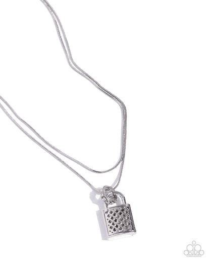 A silver necklace featuring a textured padlock pendant on a delicate chain, photographed against a clean white background with a Paparazzi logo watermark in the bottom right corner.