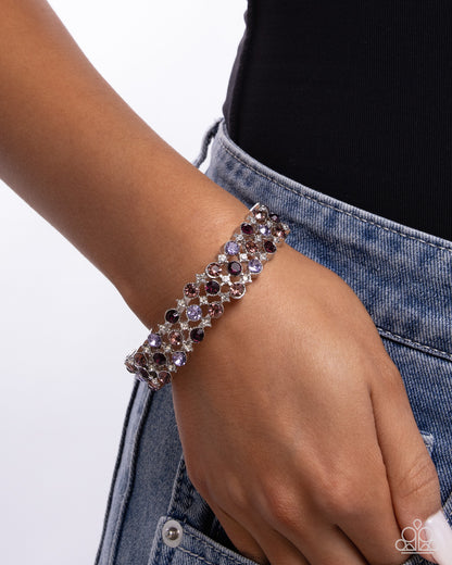 Bracelet with purple and black stones on a wrist against a white background
