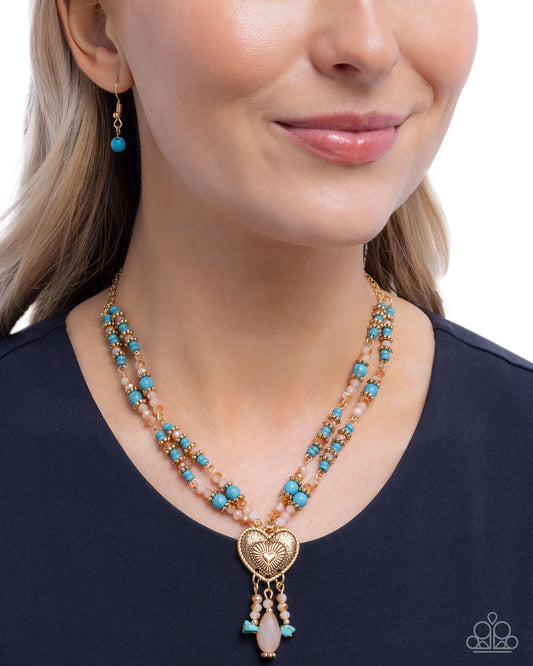 Close-up of a woman wearing a layered necklace with heart pendant and turquoise beads on a white background