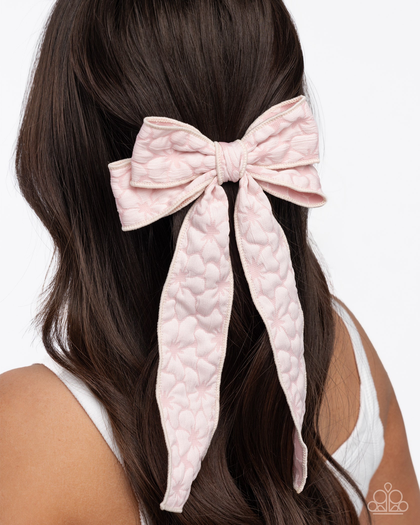 Pink textured hair bow in a person's hair on a white background