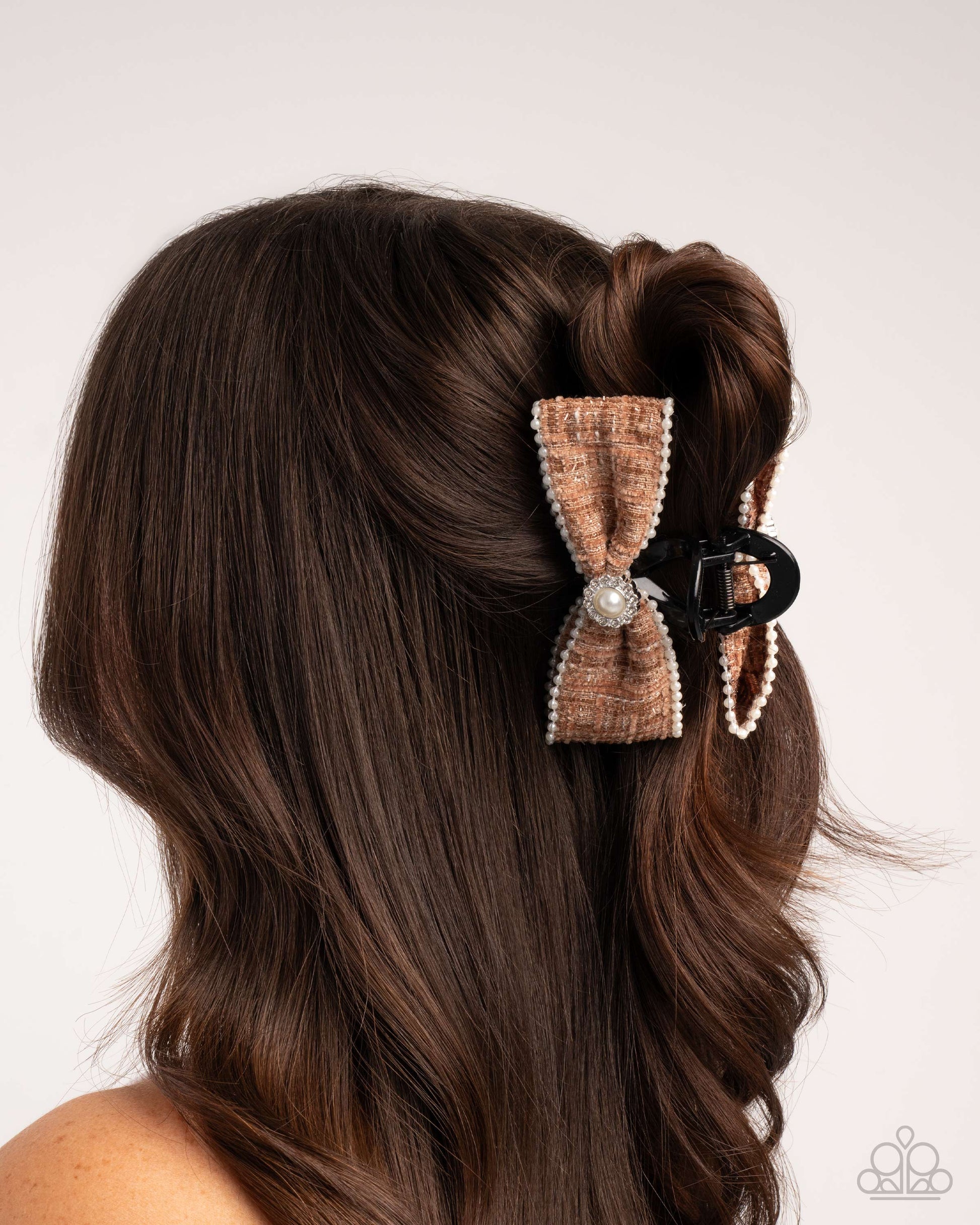 Hair styled with a decorative bow clip on a plain background