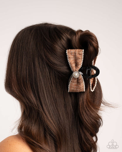 Hair styled with a decorative bow clip on a plain background