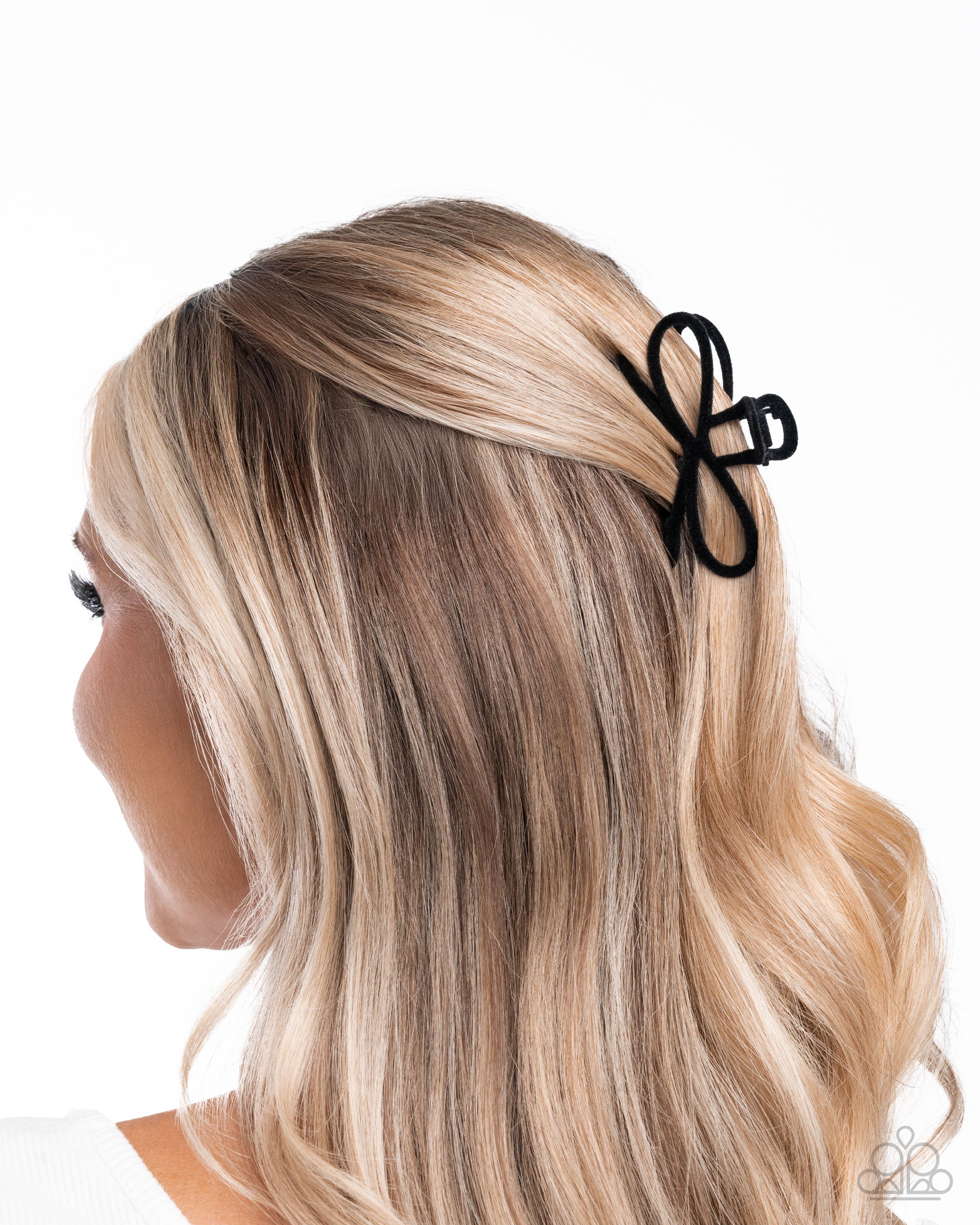 Black butterfly hair clip on a person with blonde hair against a white background