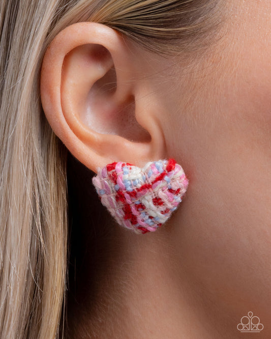 Heart-shaped beaded earring worn on an ear with a blurred background