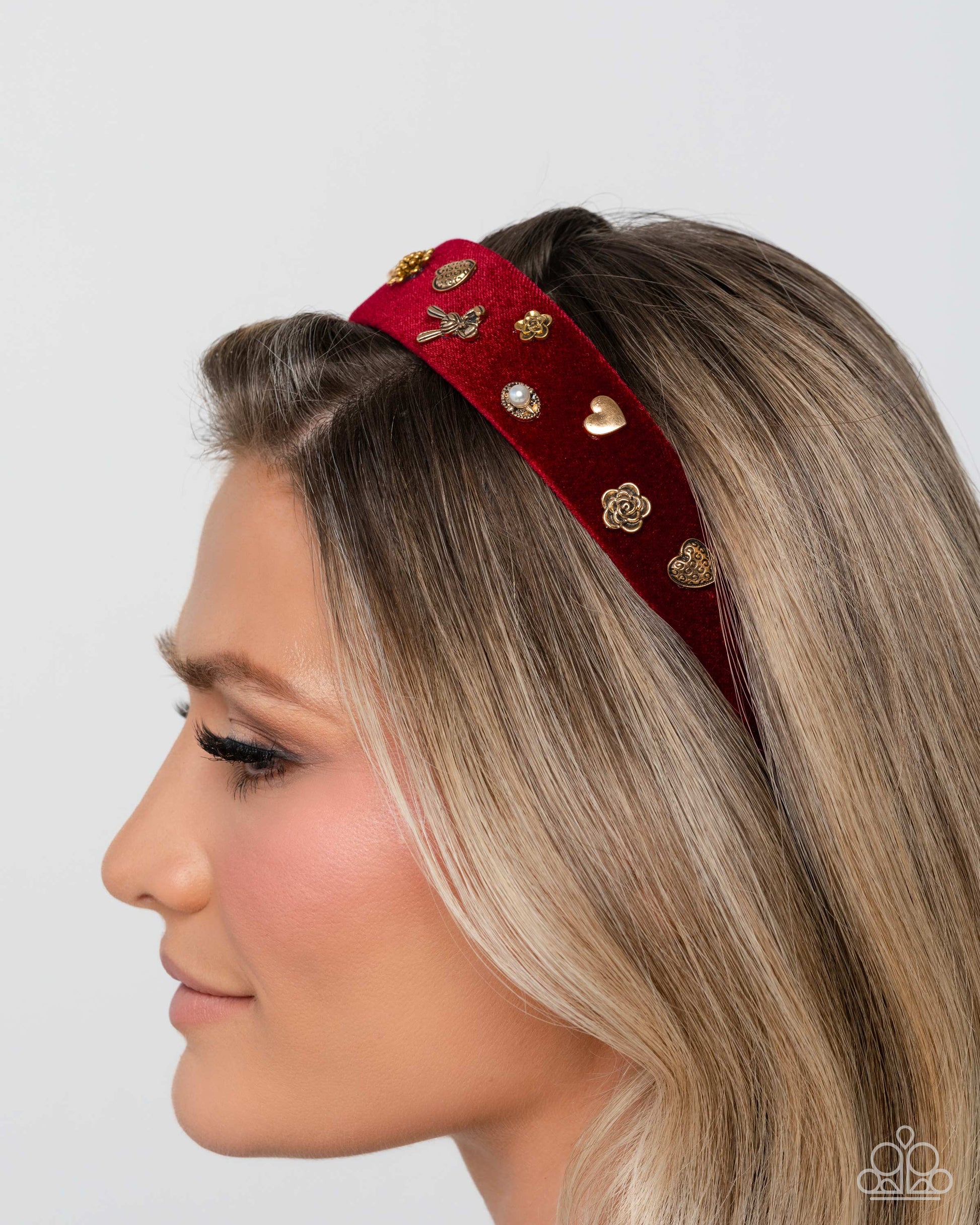 Woman wearing a red headband with gold embellishments on a plain background
