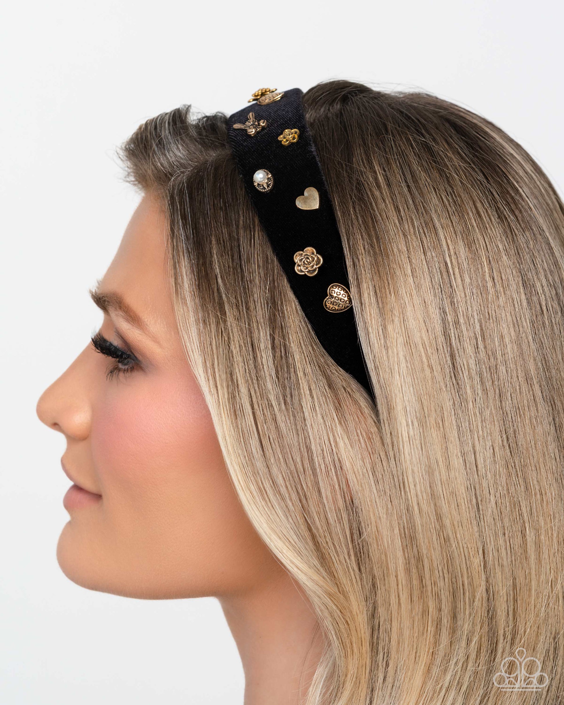 Woman wearing a decorative black headband with gold embellishments on a white background