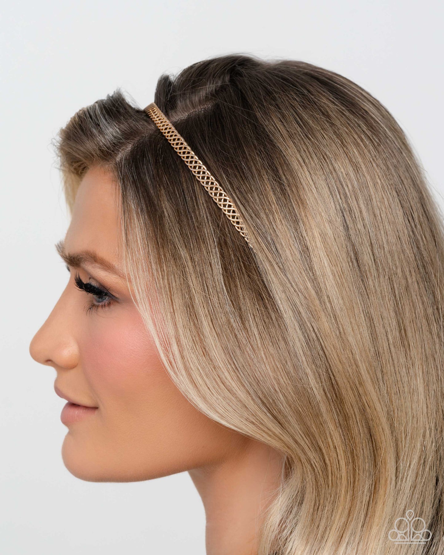 Woman wearing a gold headband with a plain background