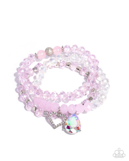 Pink beaded bracelet with a heart-shaped charm on a white background