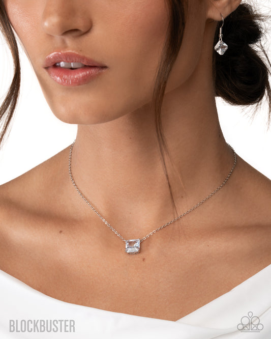 Close-up of a woman wearing a silver necklace with a clear pendant on a white background.