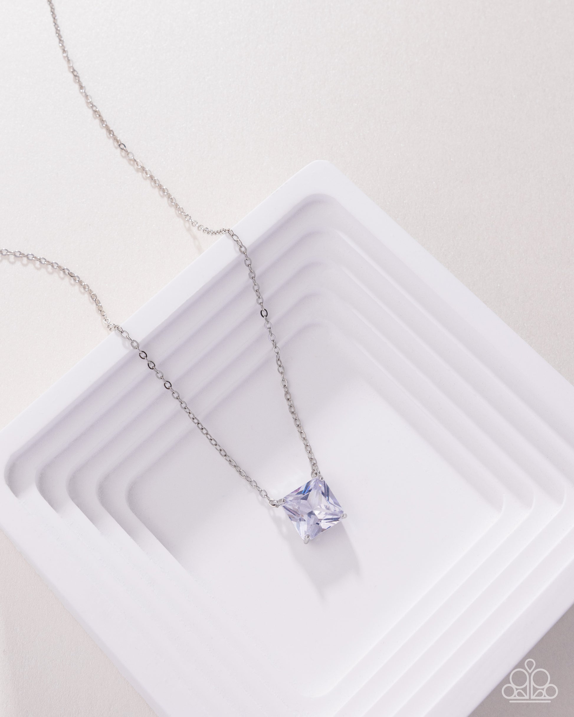 Silver necklace with a purple gemstone on a white background