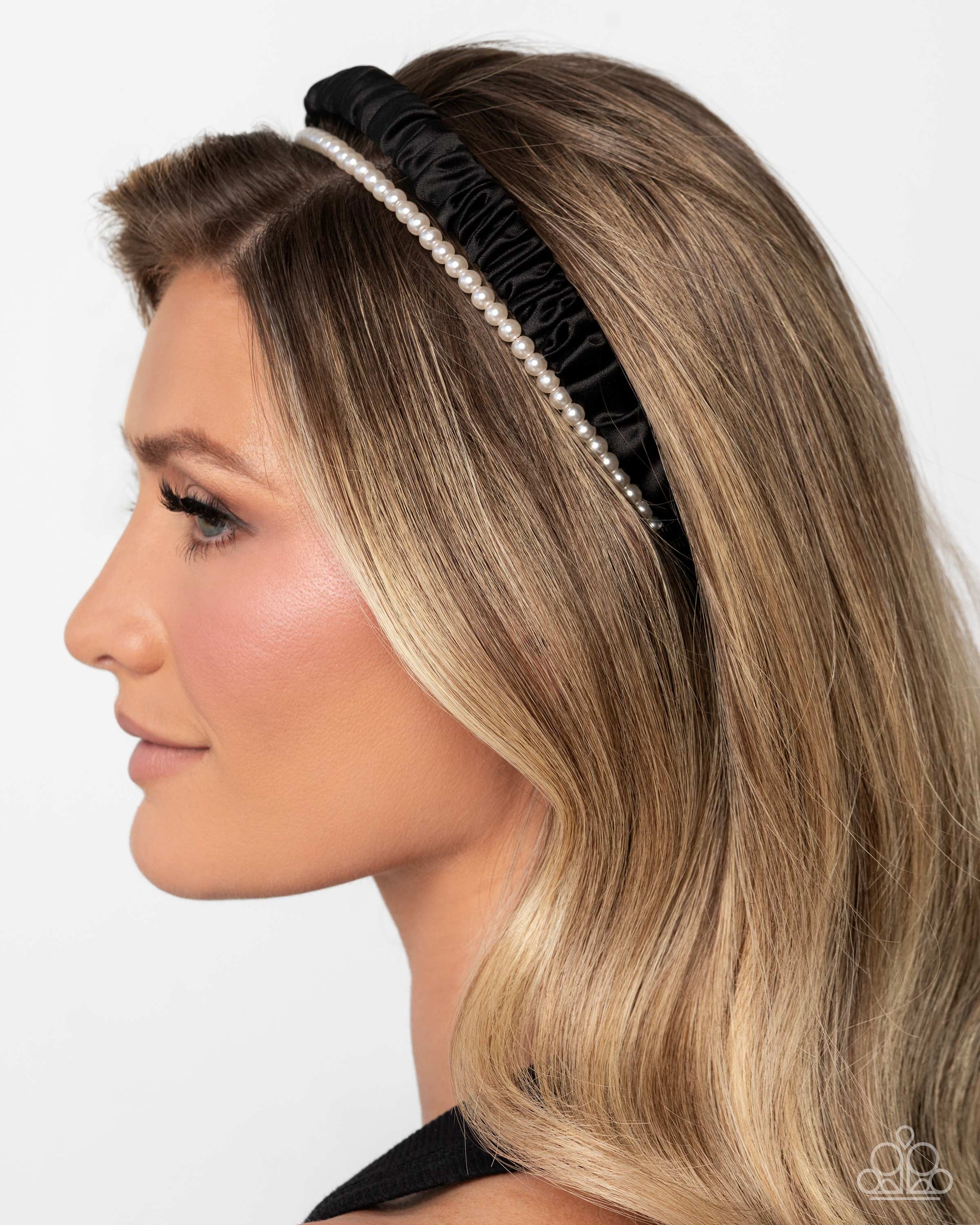 Woman wearing a black headband with pearls on a white background