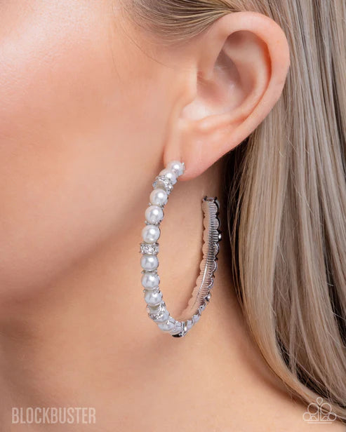 Close-up of a person wearing silver hoop earrings with a blurred background
