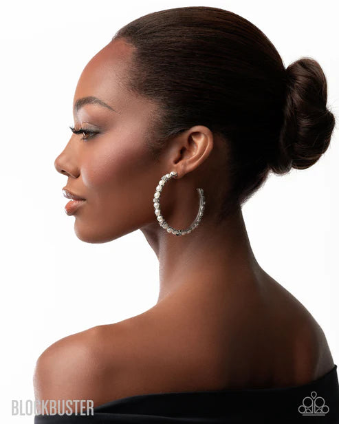 Woman wearing large hoop earrings with a side profile on a white background